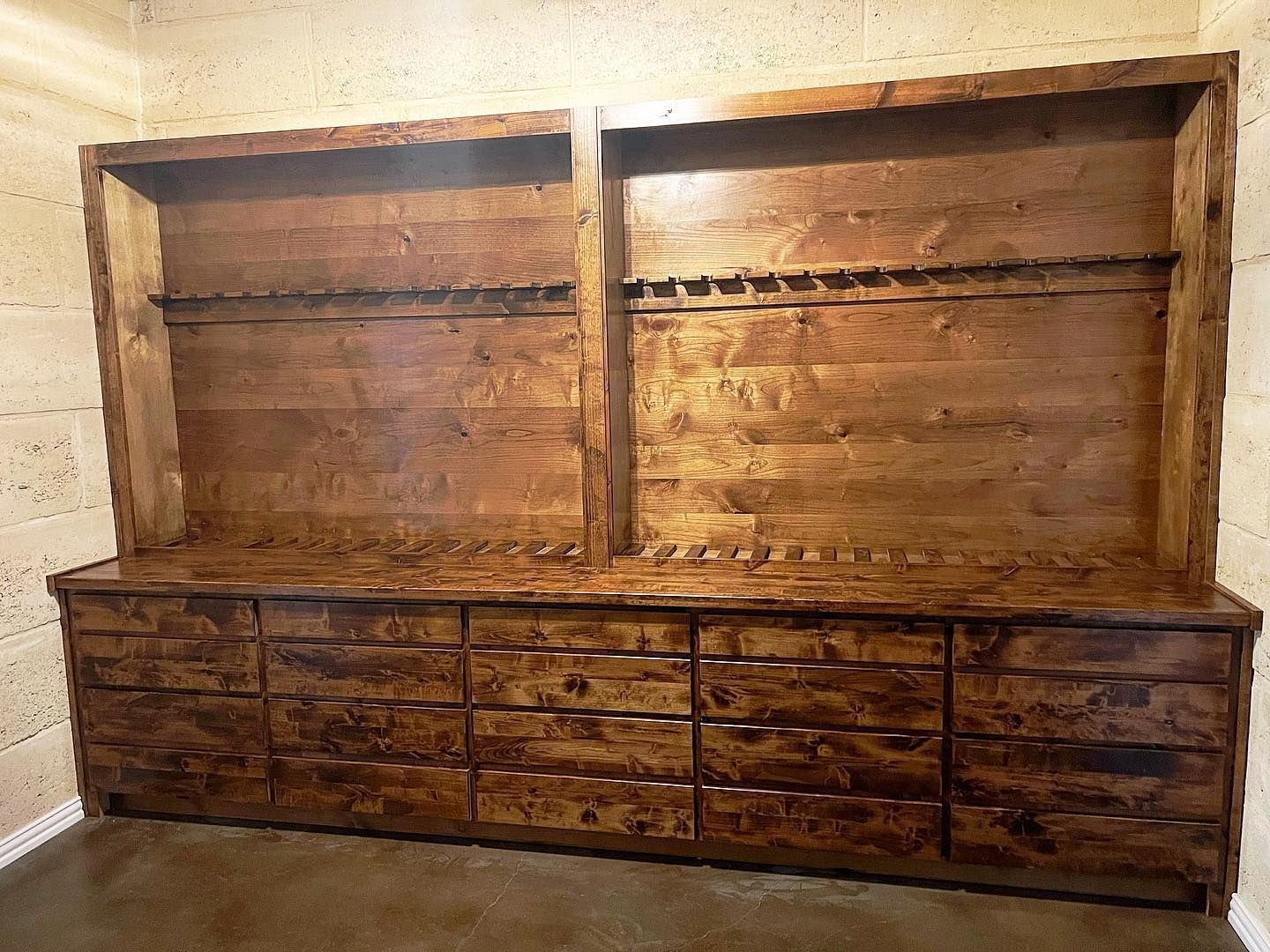 Wooden gun cabinet with two upper shelves and multiple drawers.