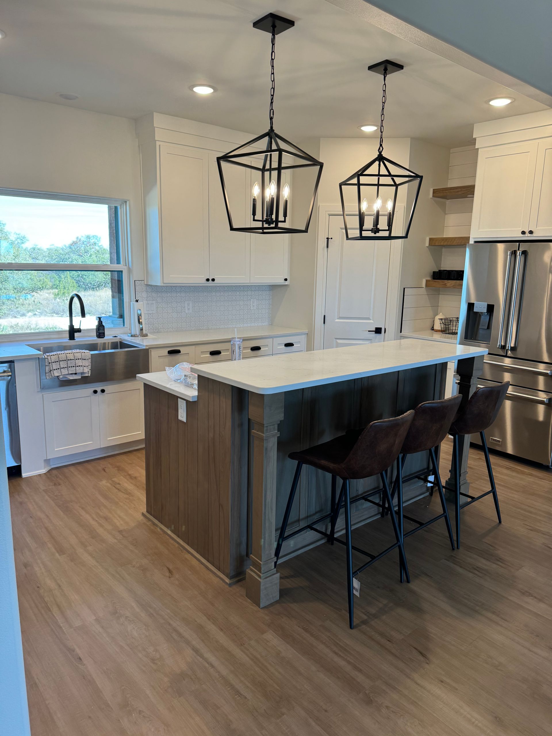 Modern kitchen with white cabinets, wood island, pendant lights, and stainless steel appliances.