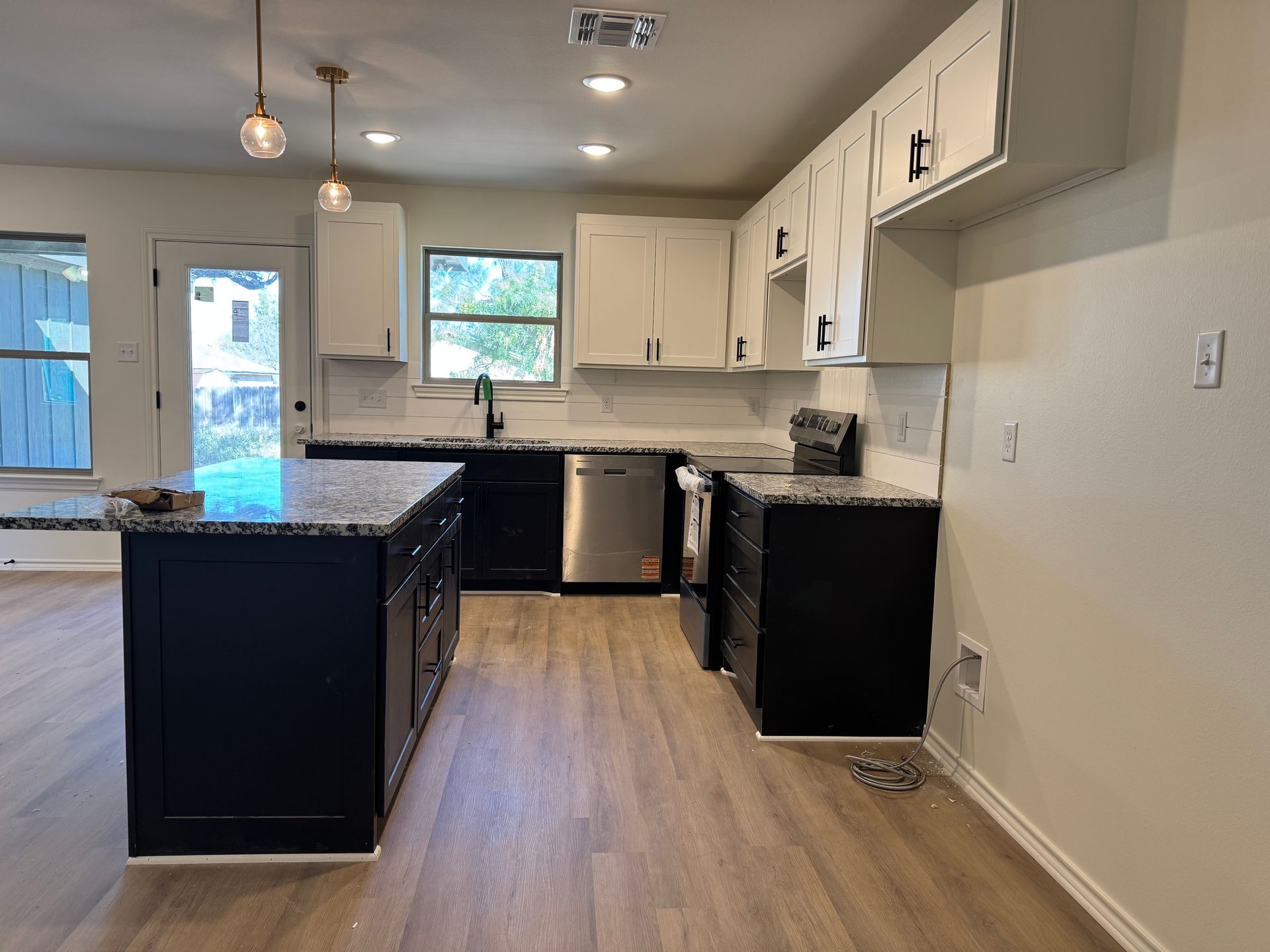 Modern kitchen with white and black cabinets, granite countertops, and stainless steel appliances.