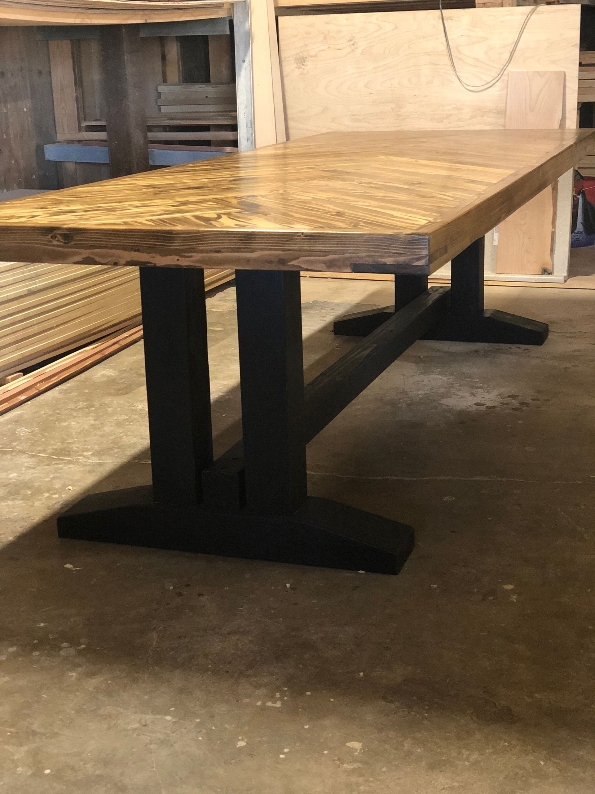 Wooden dining table with black trestle legs, indoors.