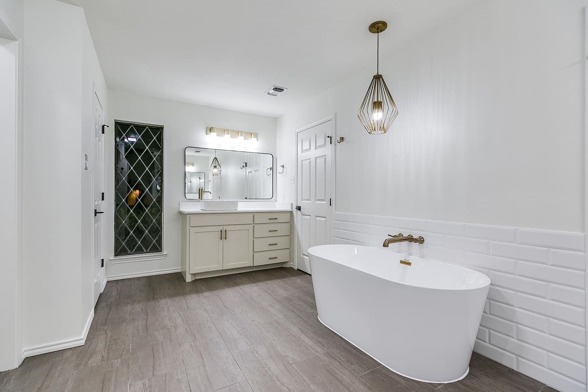 White bathroom with freestanding tub, vanity, and decorative lighting.