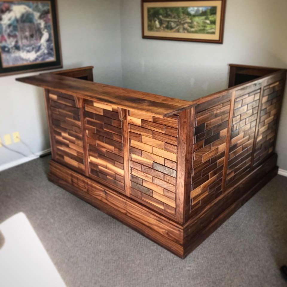 Wooden bar with a textured front, in a room with paintings on the walls.