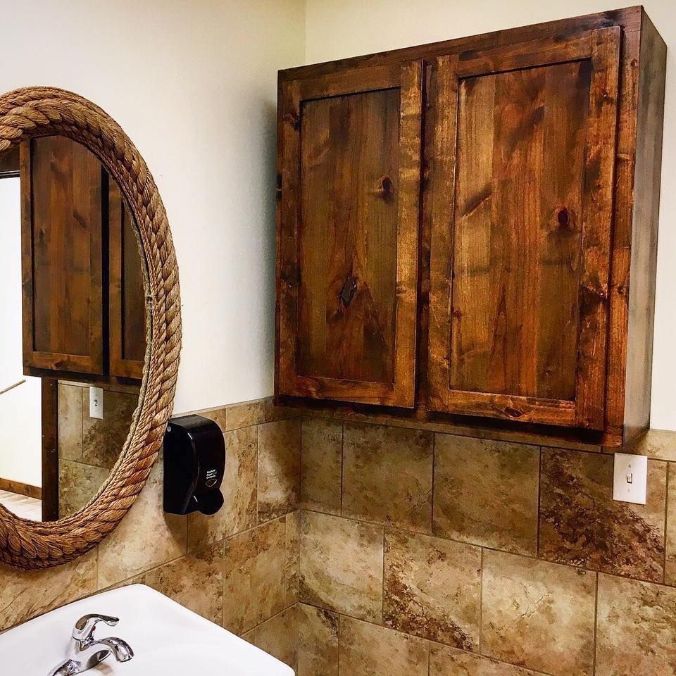 Bathroom with wood cabinet, mirror, sink, and tiled walls.