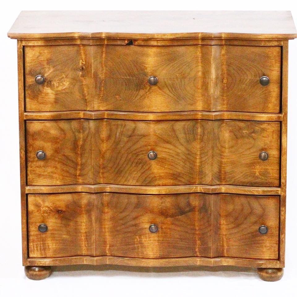 Wooden three-drawer dresser with wavy drawer fronts and round knobs on a white background.