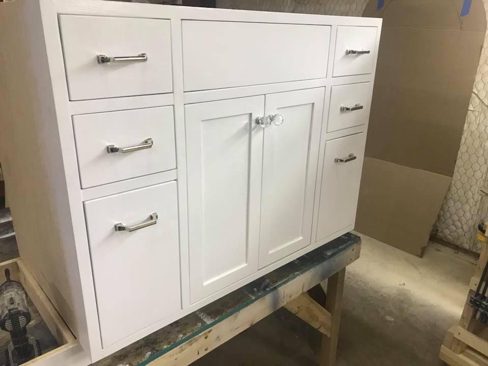 White bathroom vanity cabinet with drawers and doors; chrome handles.