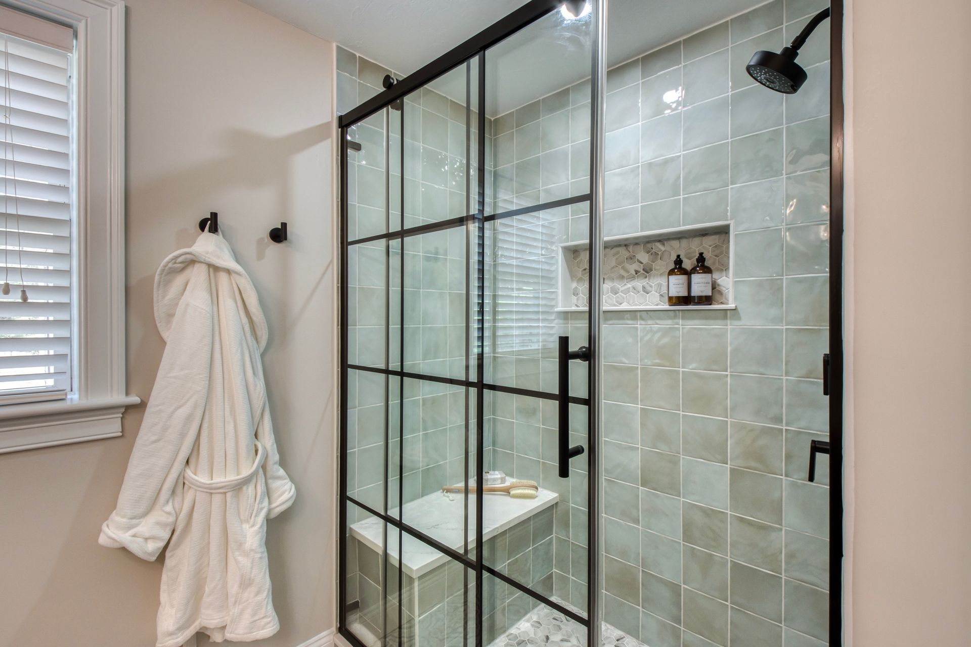 A black GMC pickup truck parked on a gravel driveway, pulling a flatbed trailer with an orange excavator.