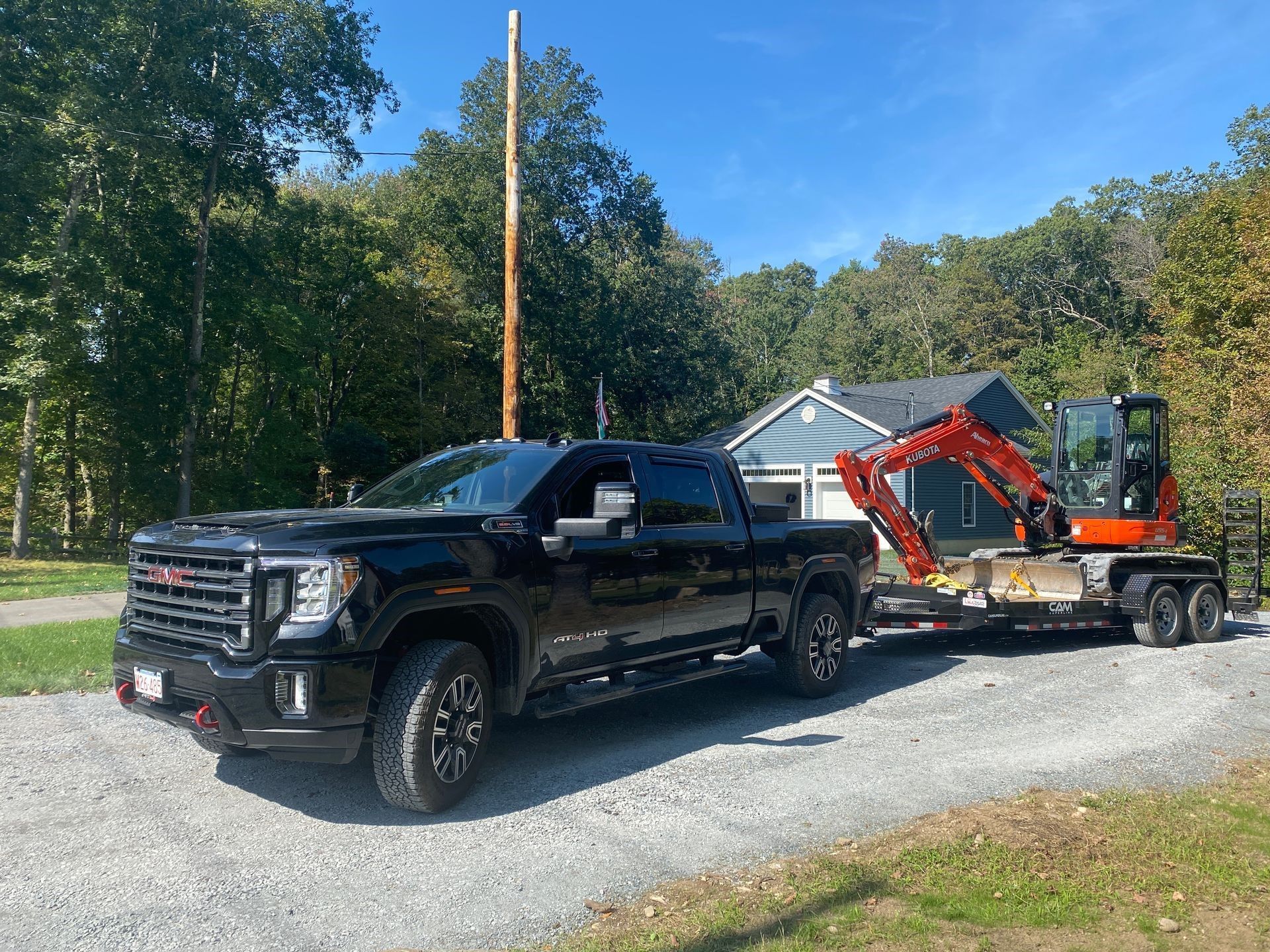 a black truck is towing a red excavator on a trailer.