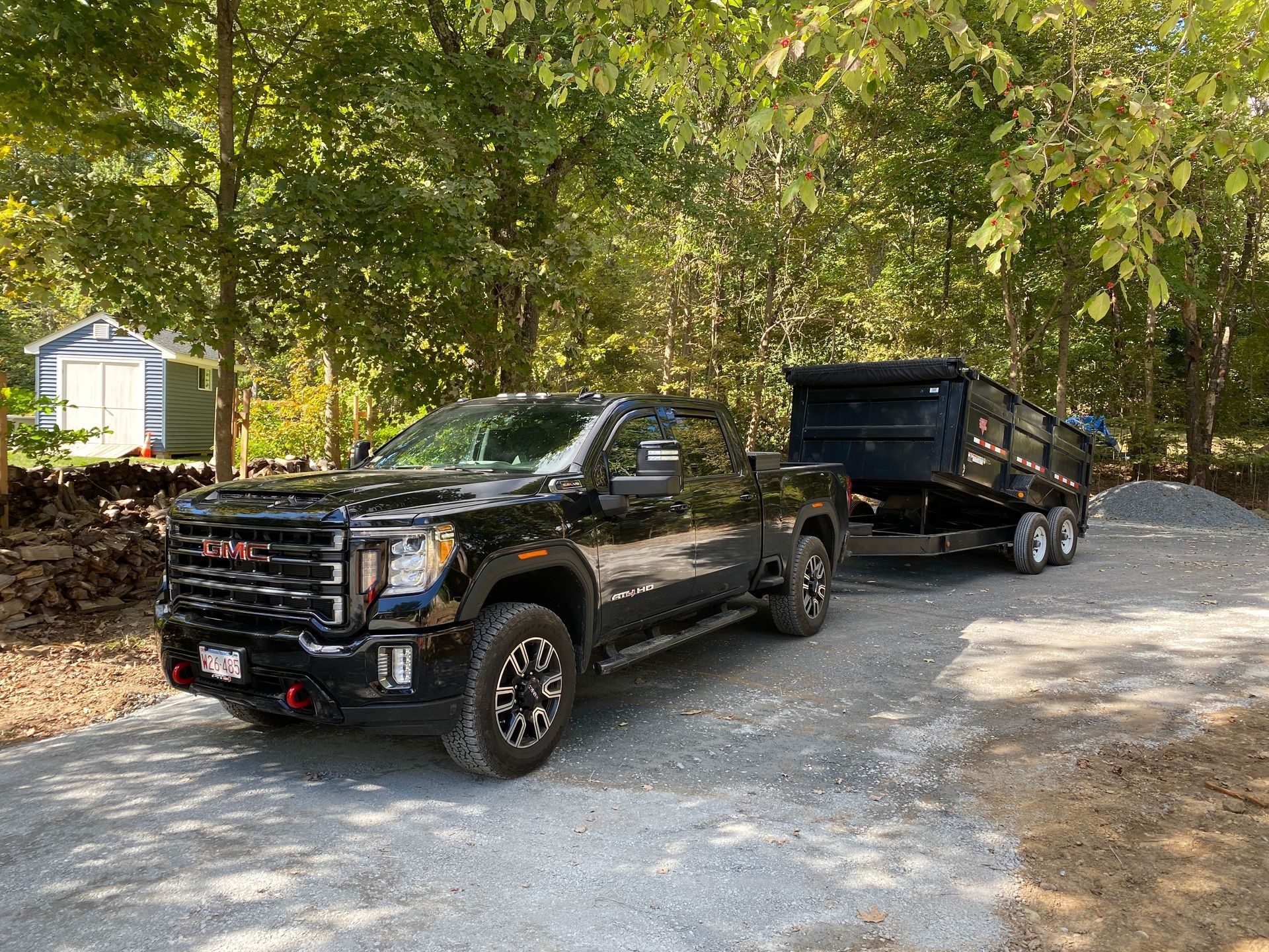 a black gmc truck is towing a dump truck down a dirt road.