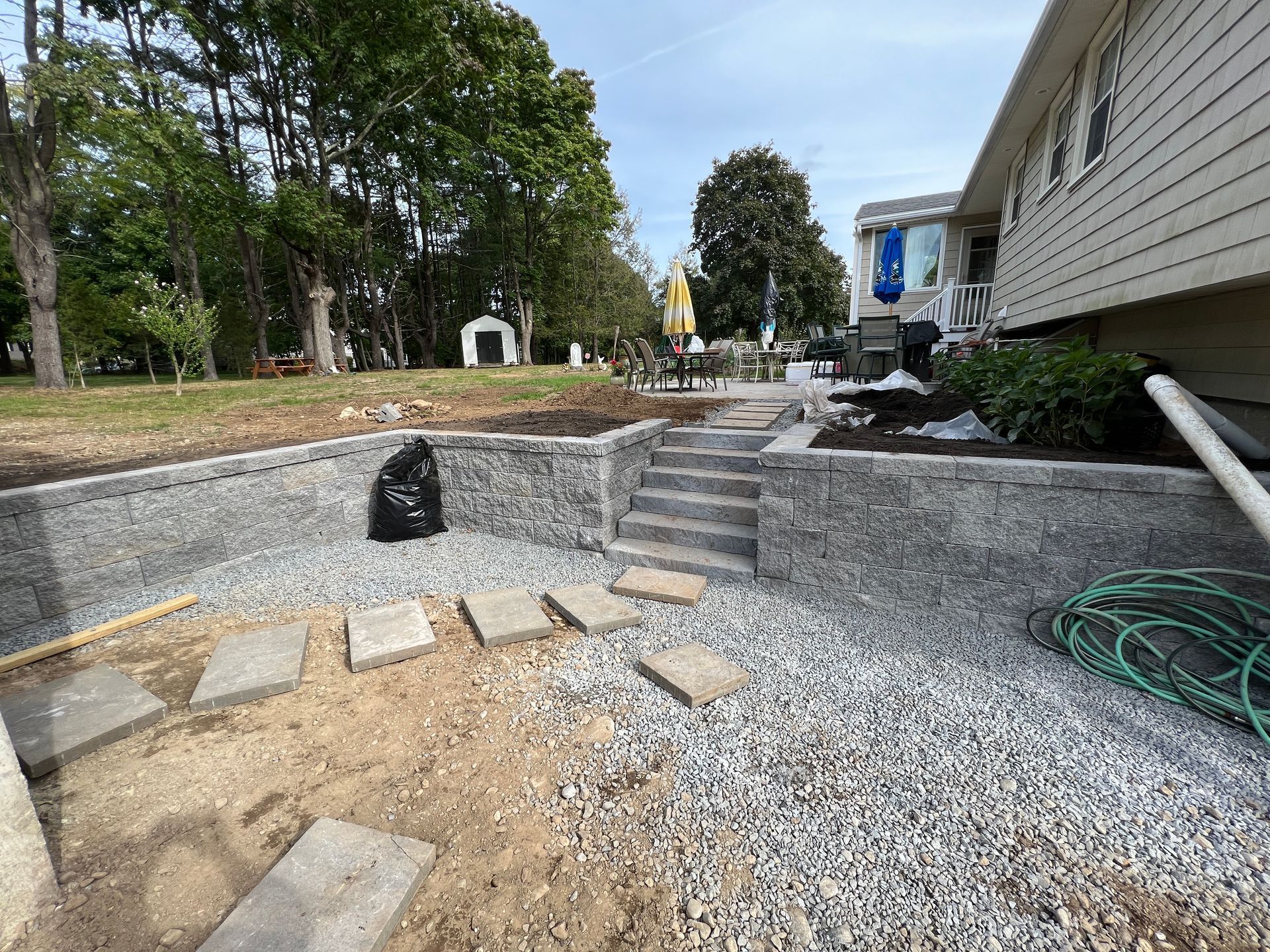 a house is being built next to a gravel area with stairs and a hose.