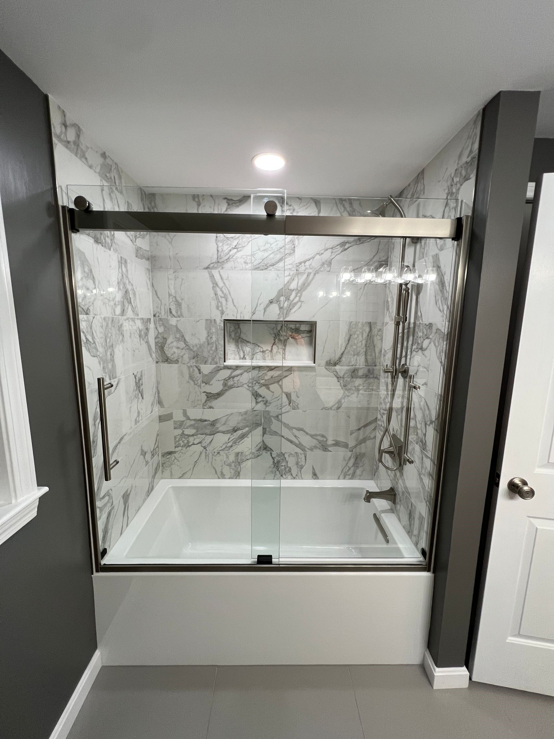 a bathroom with a bathtub and a sliding glass shower door