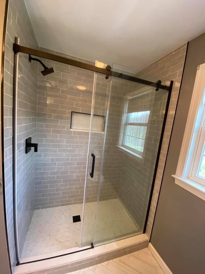 a bathroom with a sliding glass shower door and a window.