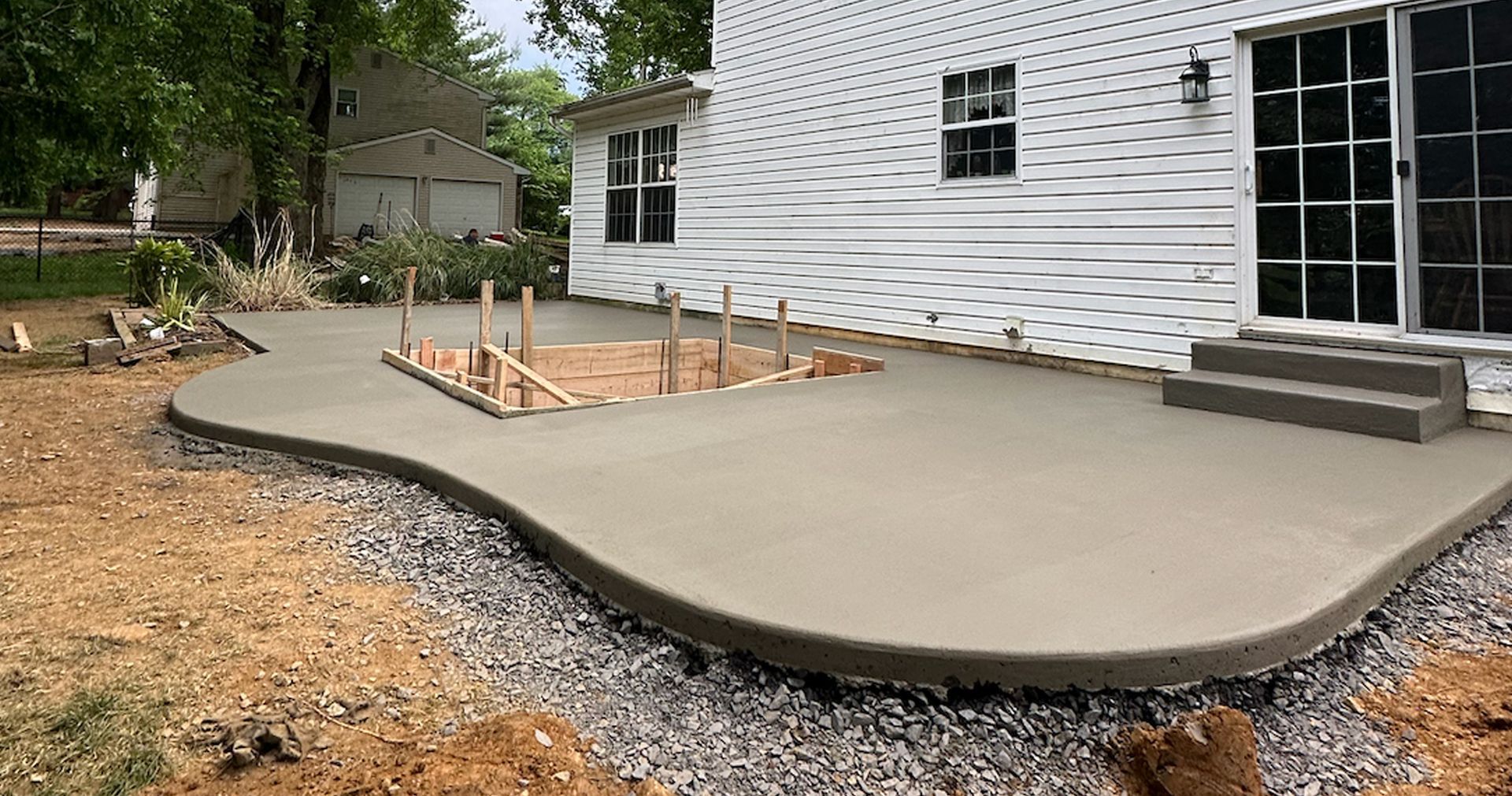 A concrete patio is being built in front of a white house.