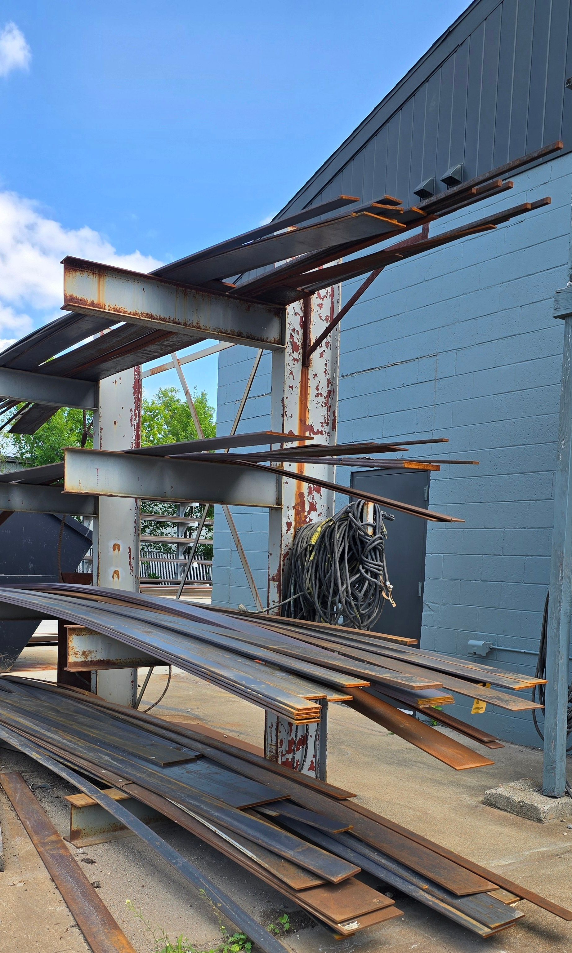 A pile of rusty metal is sitting in front of a building.