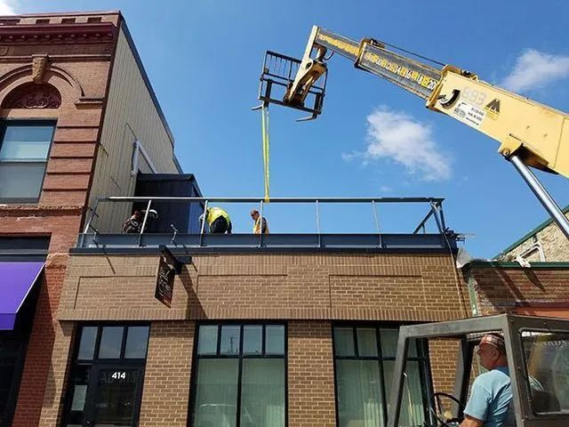 A man is working on the roof of a building with a crane.