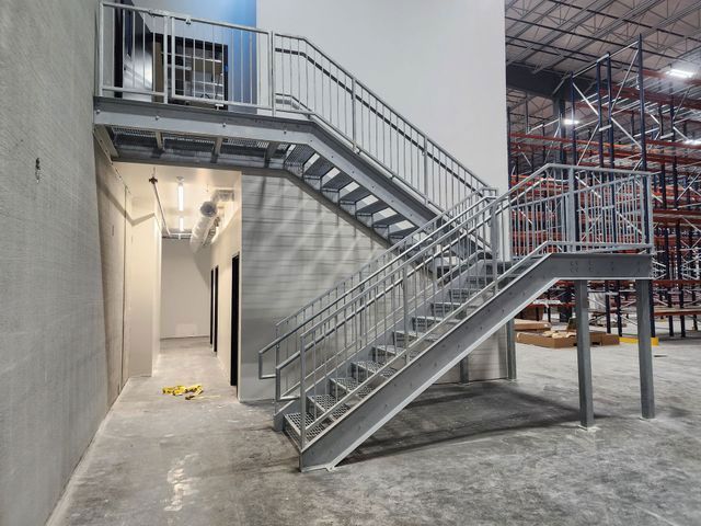 A staircase in a warehouse with a metal railing