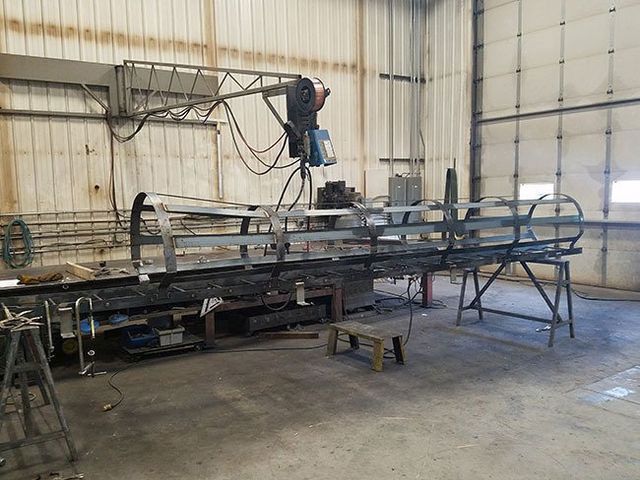 A man is welding a metal structure in a warehouse.