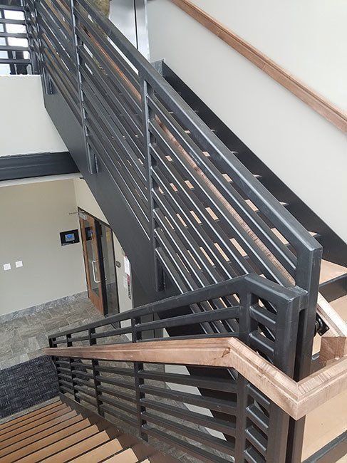 A staircase with a metal railing and wooden handrails