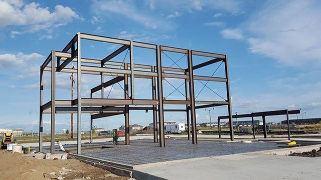 A large metal structure is being built in a field.