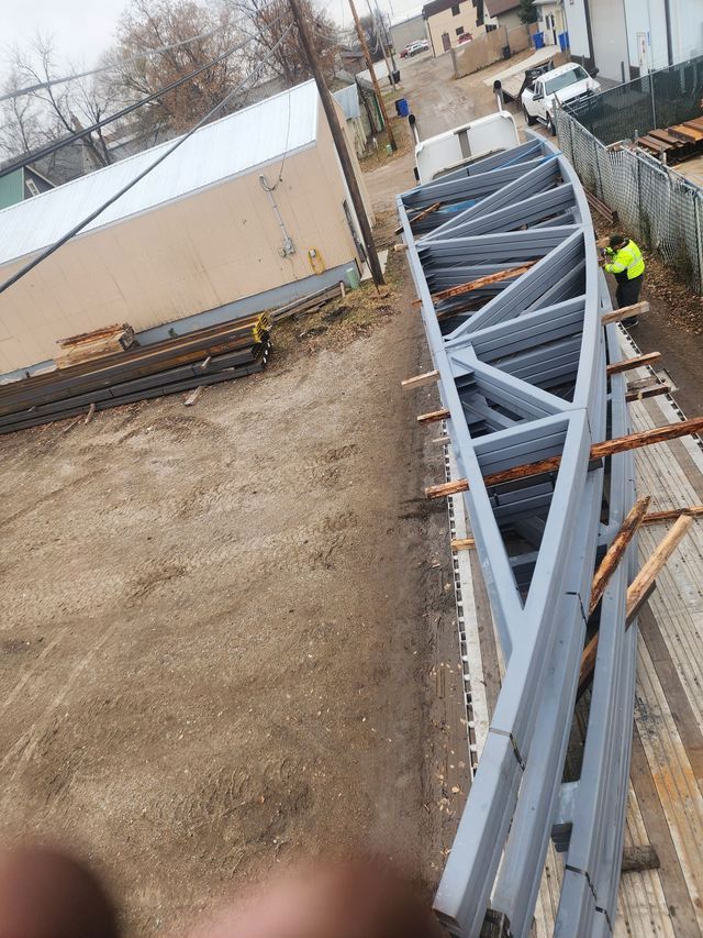 A large metal structure is being built in a dirt field.