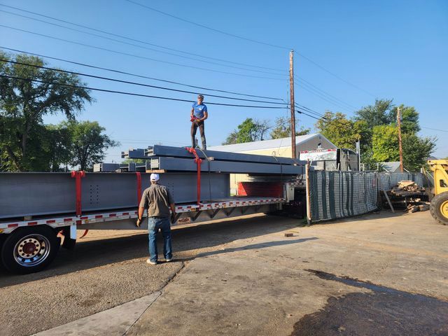 A man is standing on top of a truck carrying a large load.