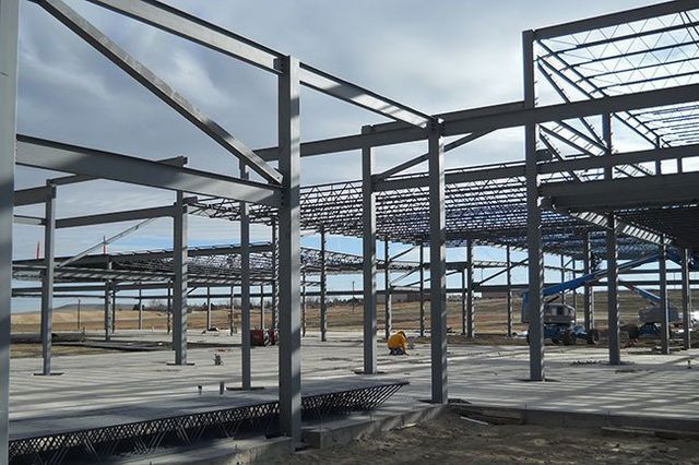 A large metal structure is under construction on a cloudy day.
