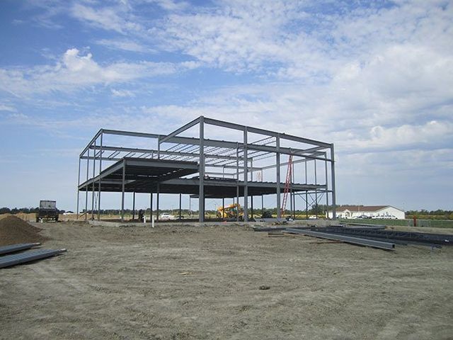 A large metal structure is being built in a dirt field.