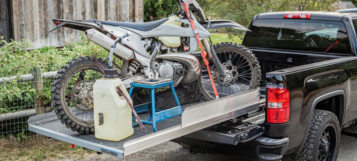A dirt bike is being towed in the back of a truck