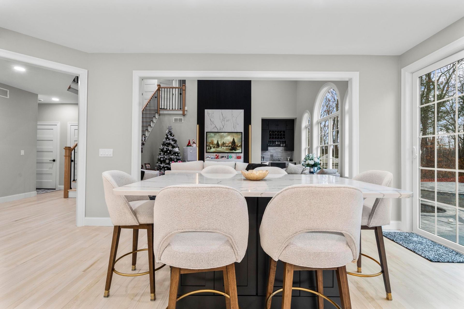 A bright dining area featuring a white kitchen island with four textured cream-colored chairs on a light wood floor.