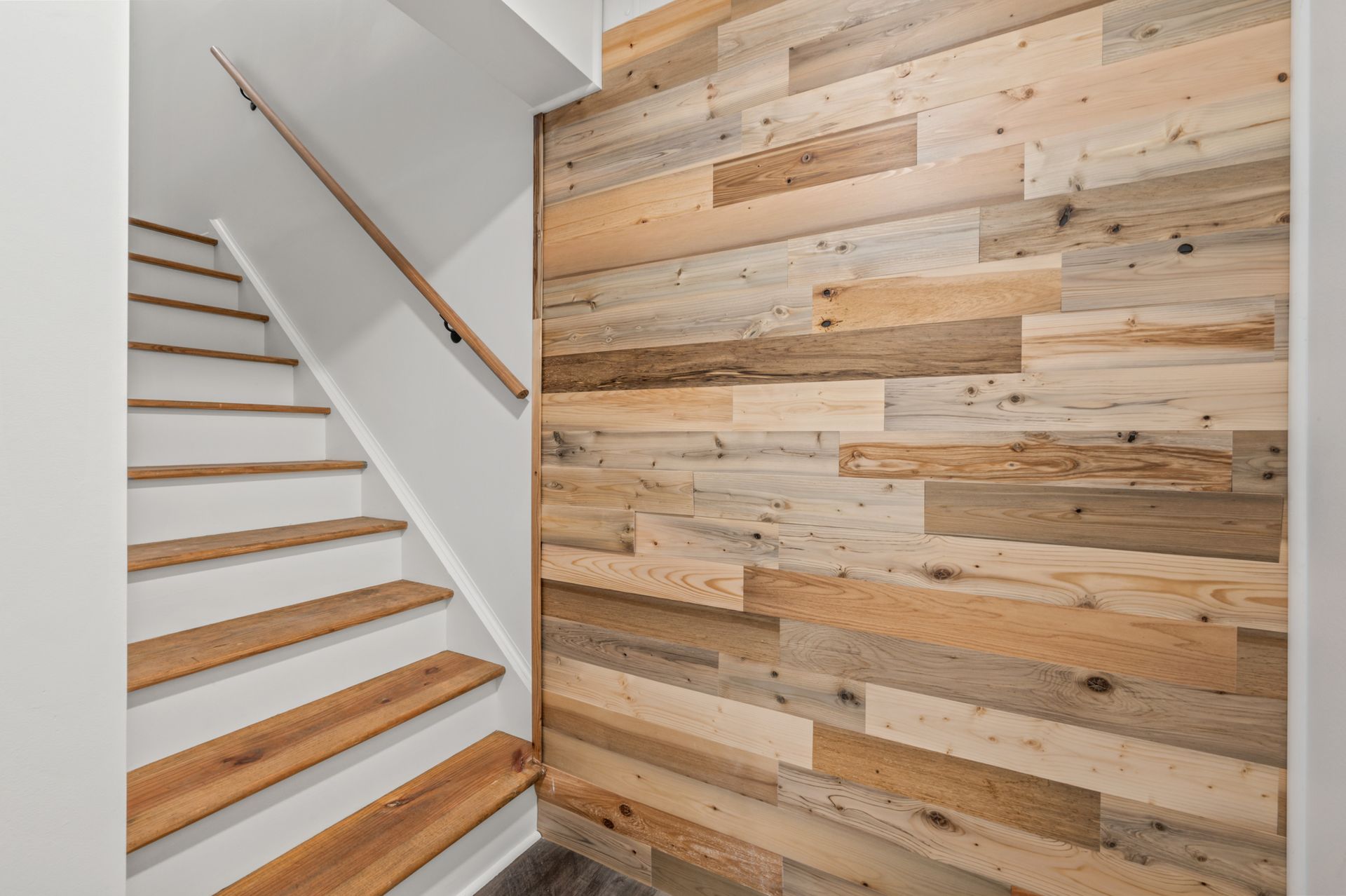 A wooden staircase with white risers and a light wood-paneled feature wall on the right.
