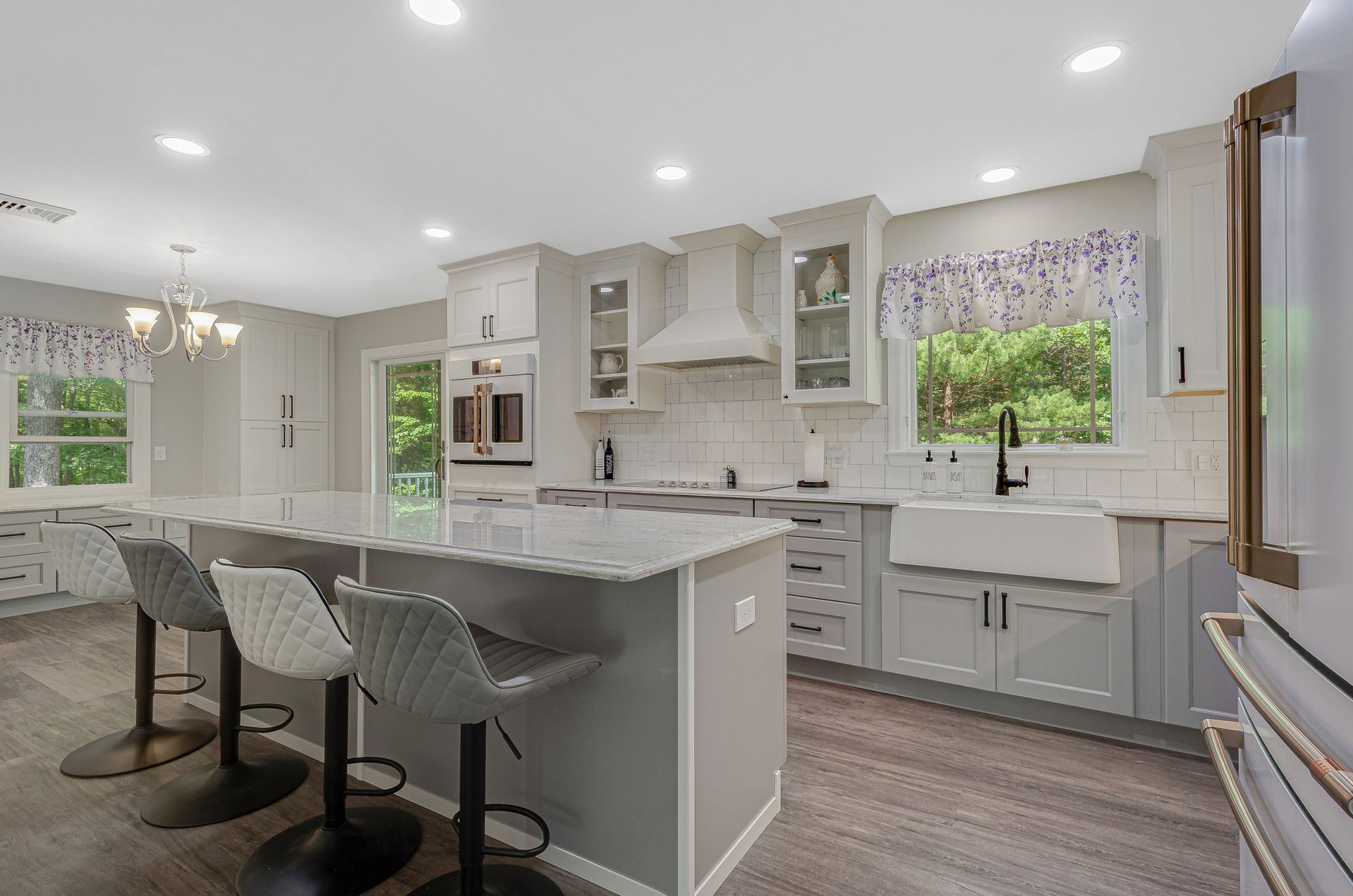 A kitchen with a large island , stools , a sink and a window.