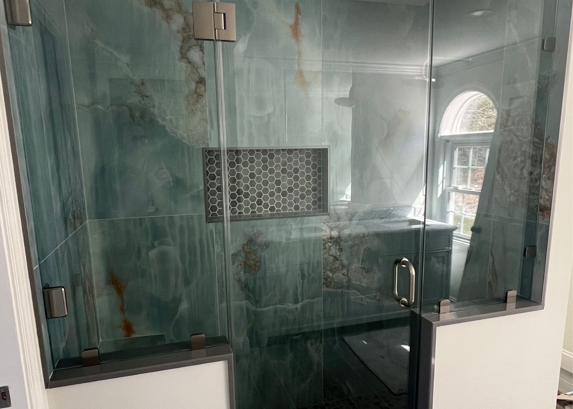 A bathroom with a walk in shower with a glass door.