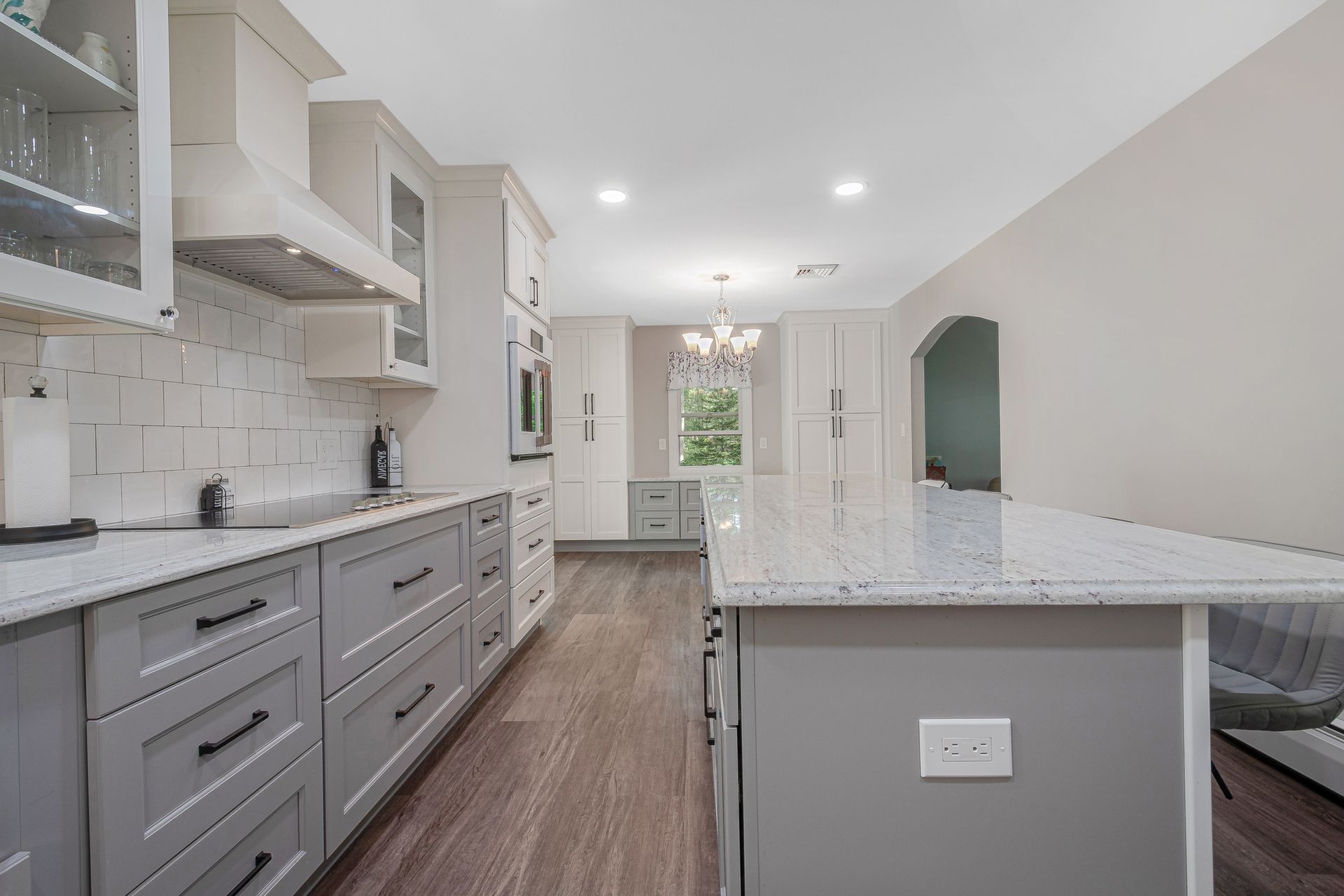 A kitchen with gray cabinets and white counter tops and a large island.