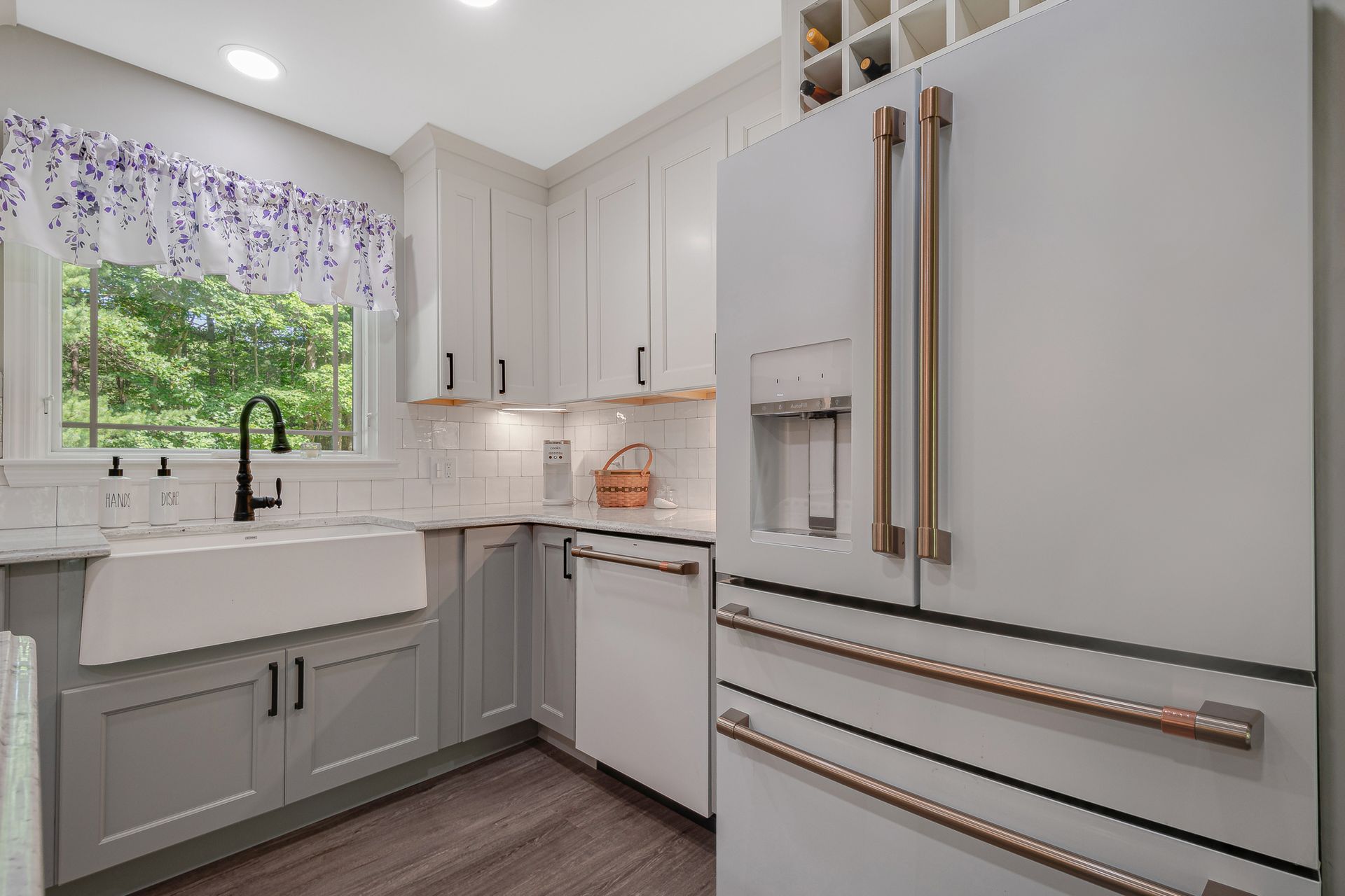 A kitchen with white cabinets , a white refrigerator , a sink , and a window.