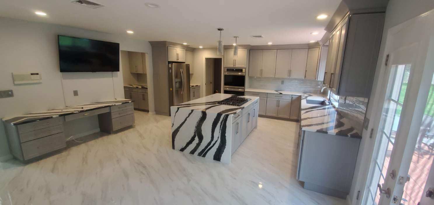 A kitchen with a large island and a flat screen tv.