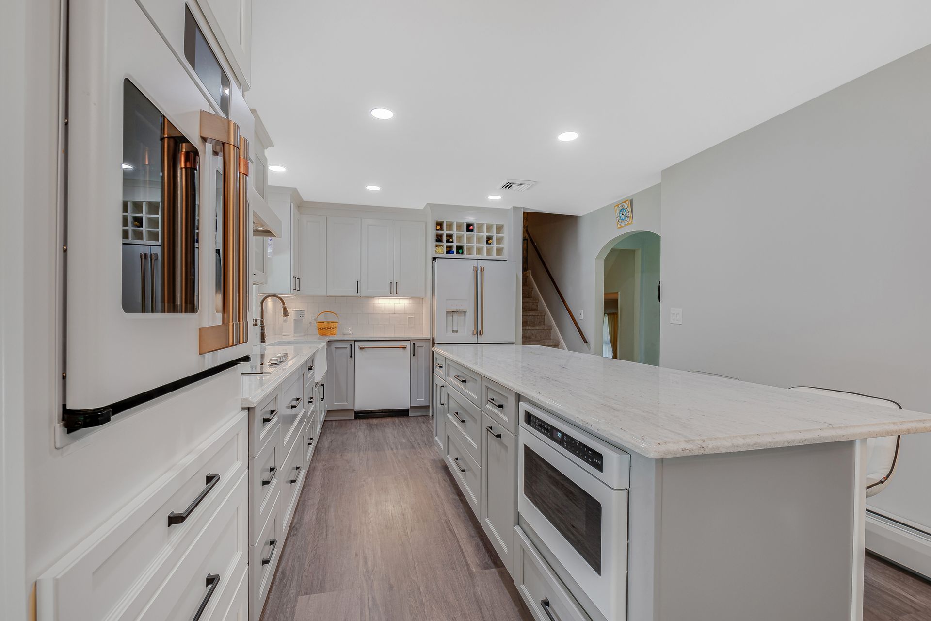 A kitchen with white cabinets , white counter tops , and a large island.