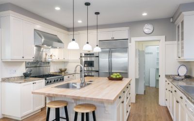 A kitchen with white cabinets , stainless steel appliances , a sink , and a large island.