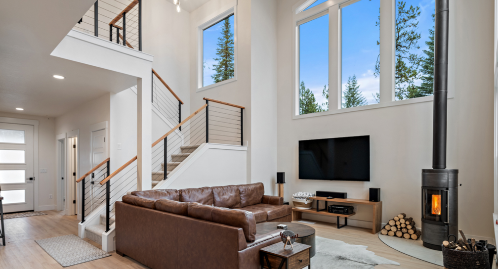 A living room with a couch, television, fireplace and stairs.
