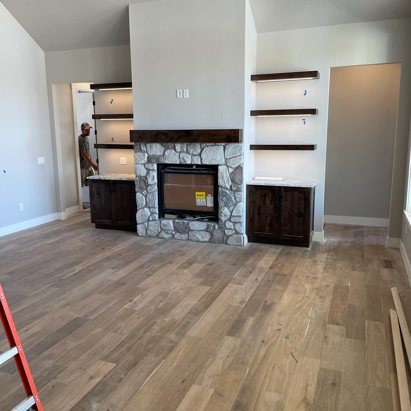 A living room with hardwood floors and a stone fireplace