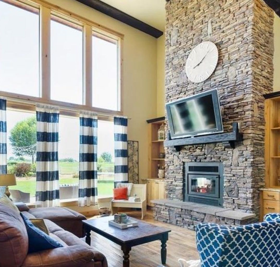 A living room with a stone fireplace and a flat screen tv