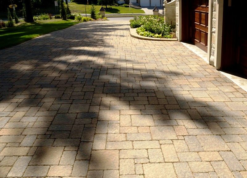 A paved residential driveway made of multi-sized, earthy-toned rectangular stones leading to a garage.