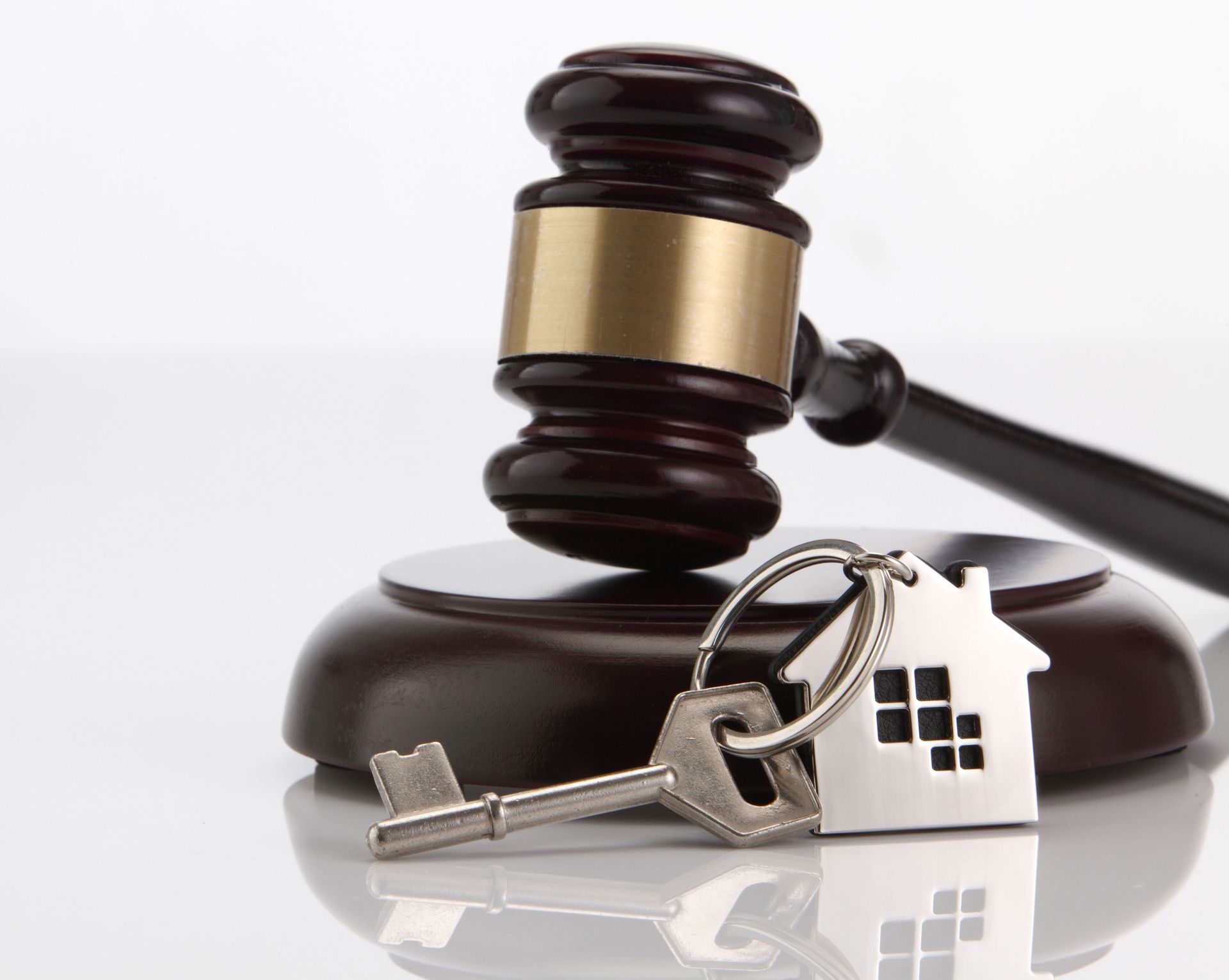 Gavel on wooden block with house key; concept of a home sale or foreclosure.