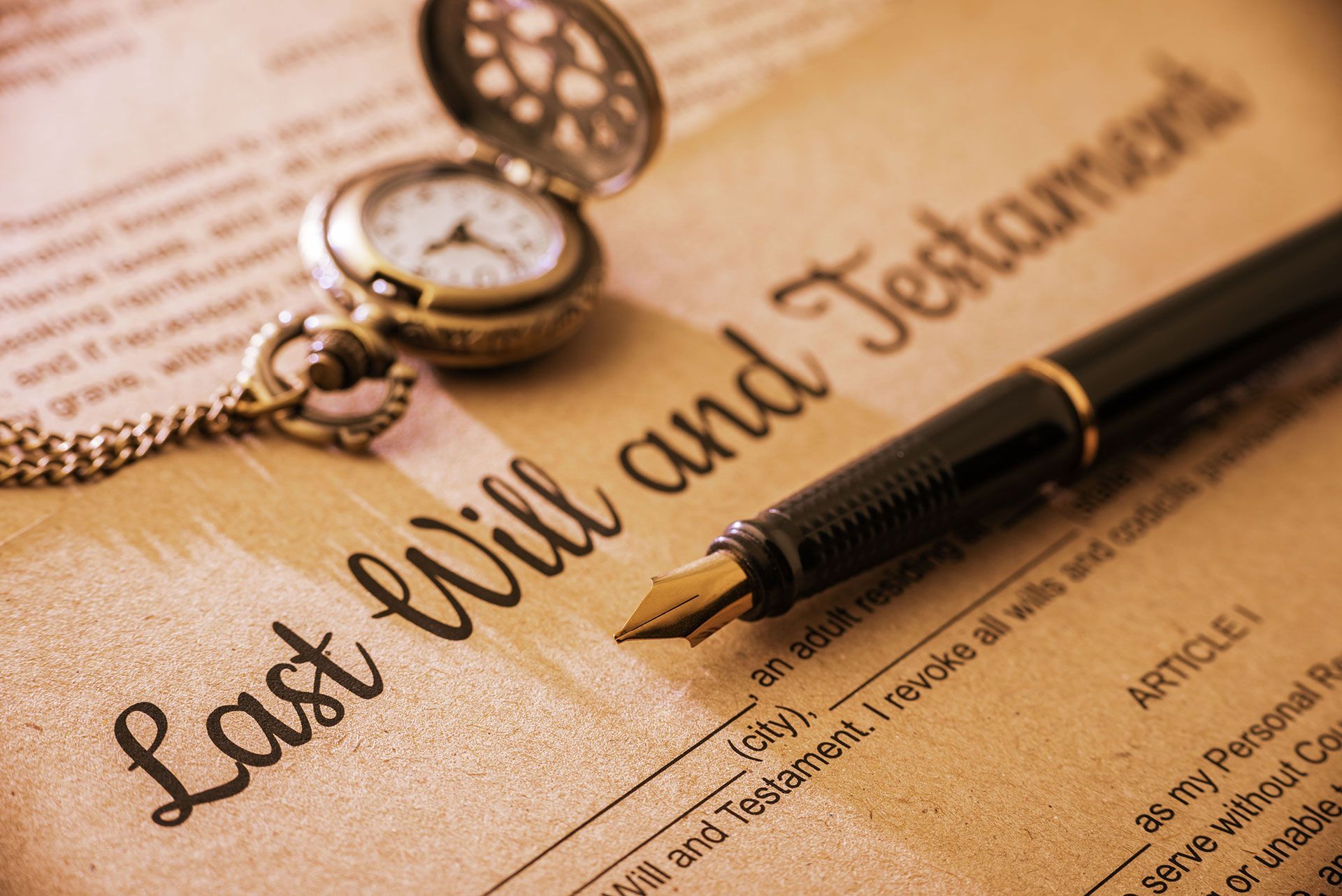 Close-up of a Last Will and Testament document with a pocket watch and fountain pen.
