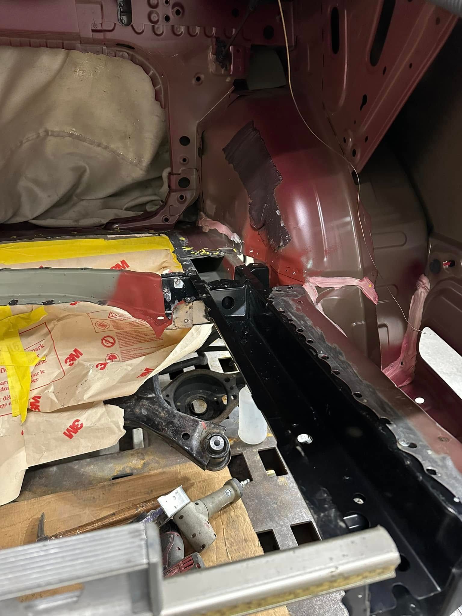 A car is being dismantled in a garage with a ladder.