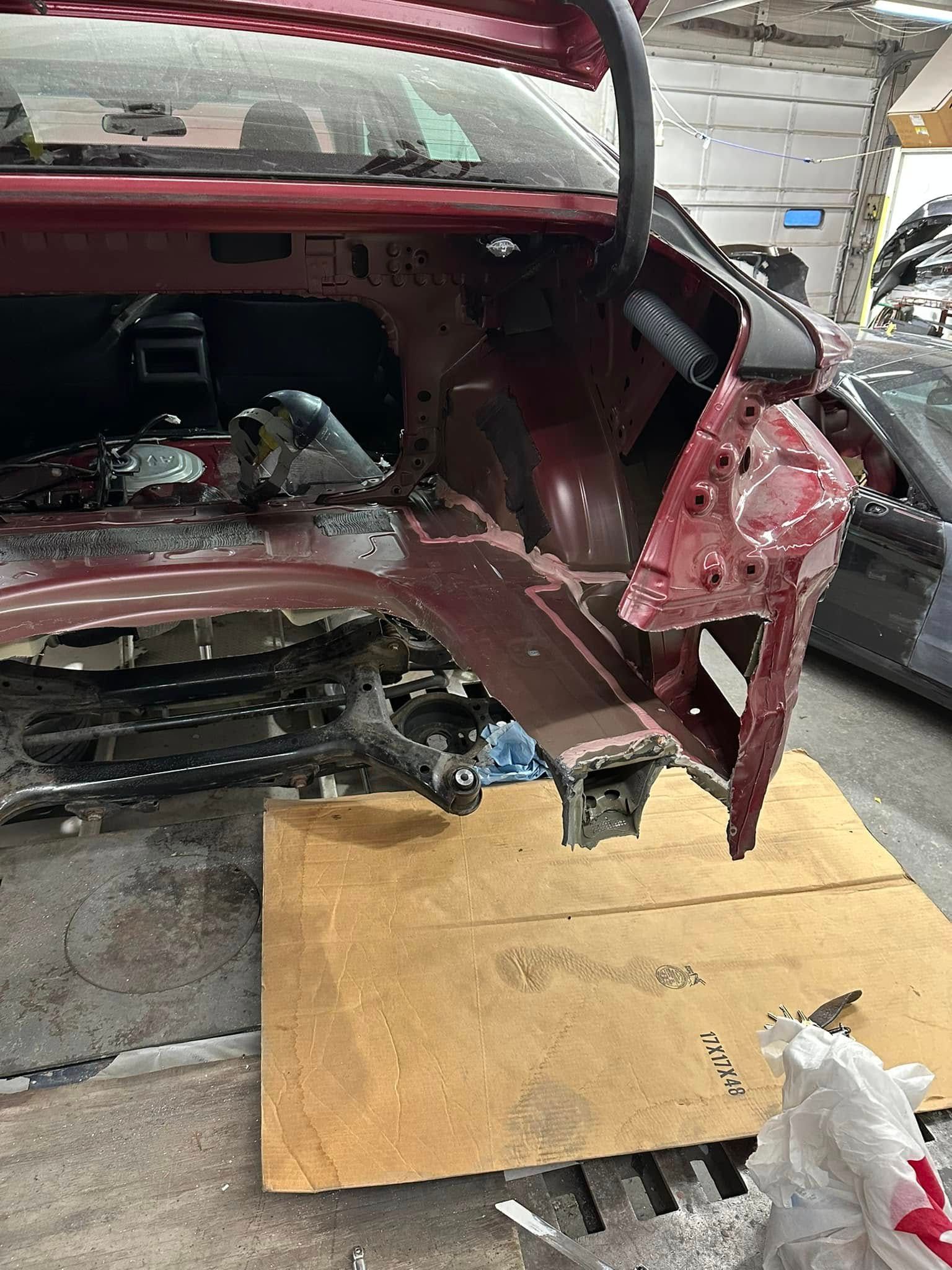 A red car is being dismantled in a garage.