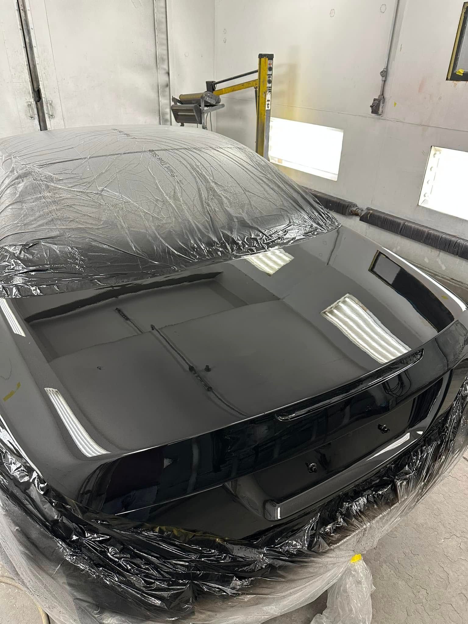 A red car is being dismantled in a garage.