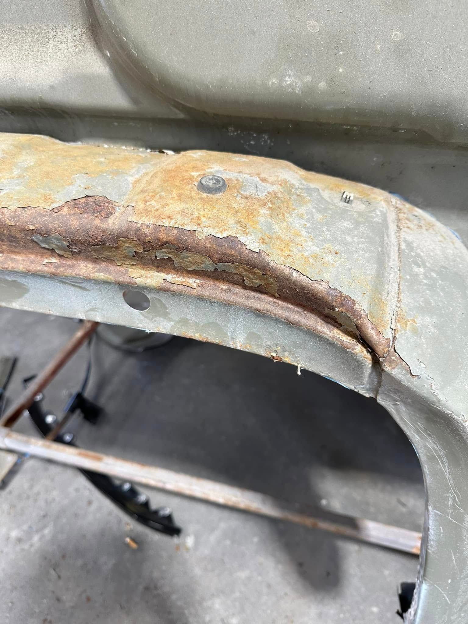 A close up of a rusty metal fender on a car.