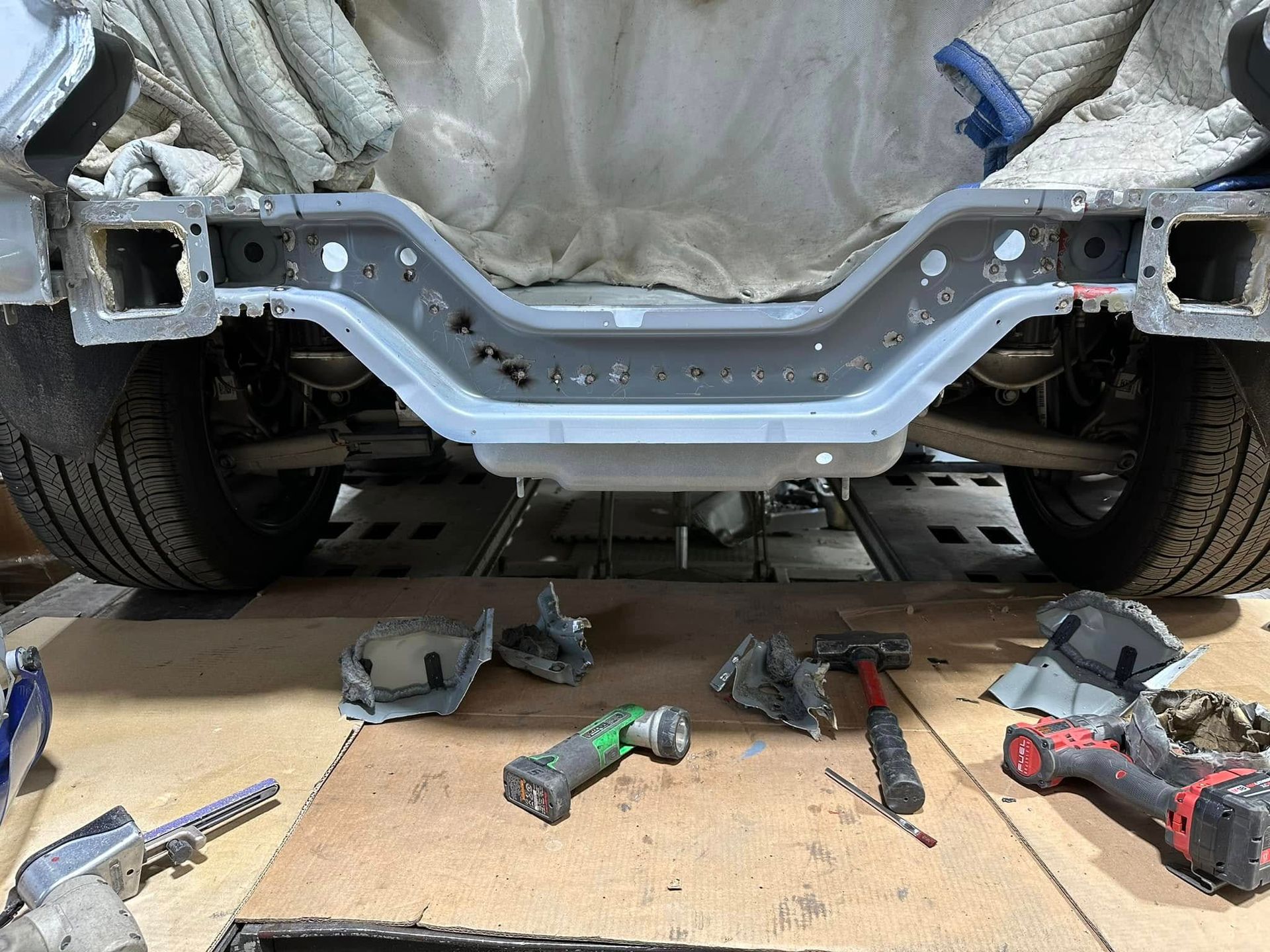 A car is being worked on in a garage with tools on the floor.