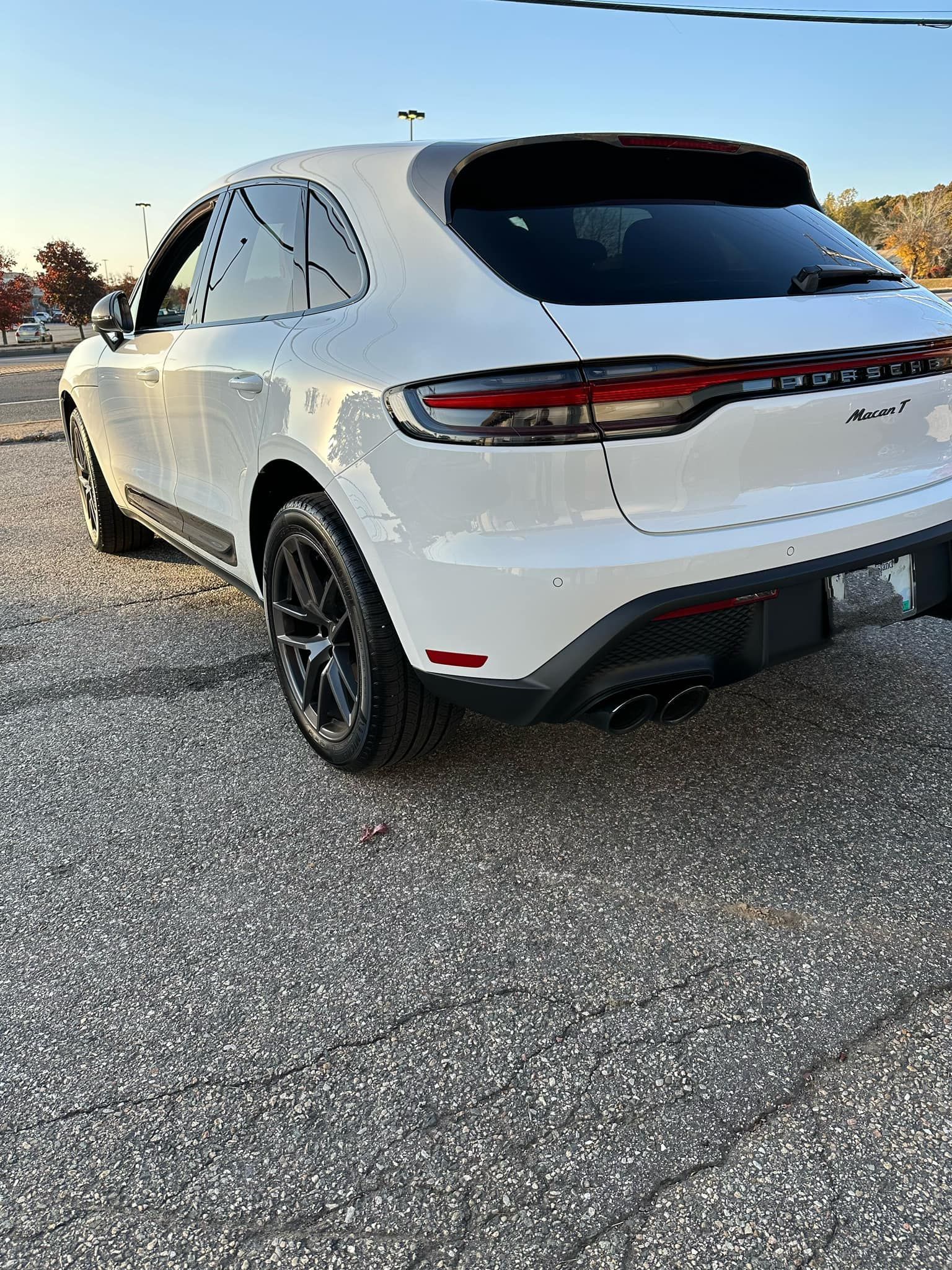 A white porsche macan turbo is parked in a gravel lot.