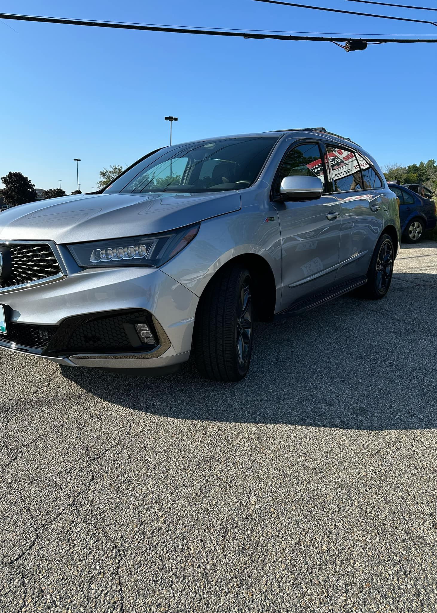 A silver suv is parked in a gravel lot.