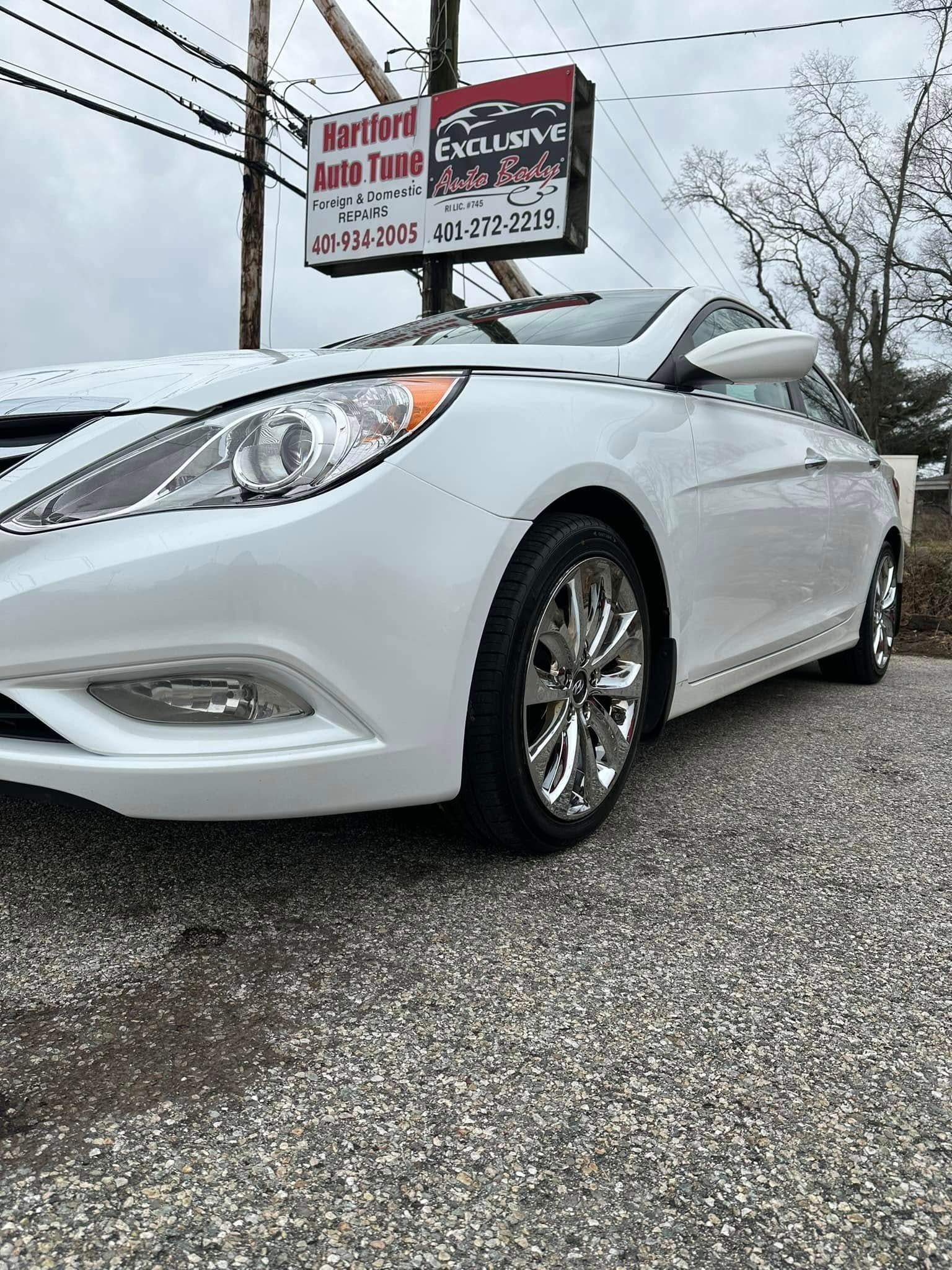 A white car is parked in front of a car dealership.